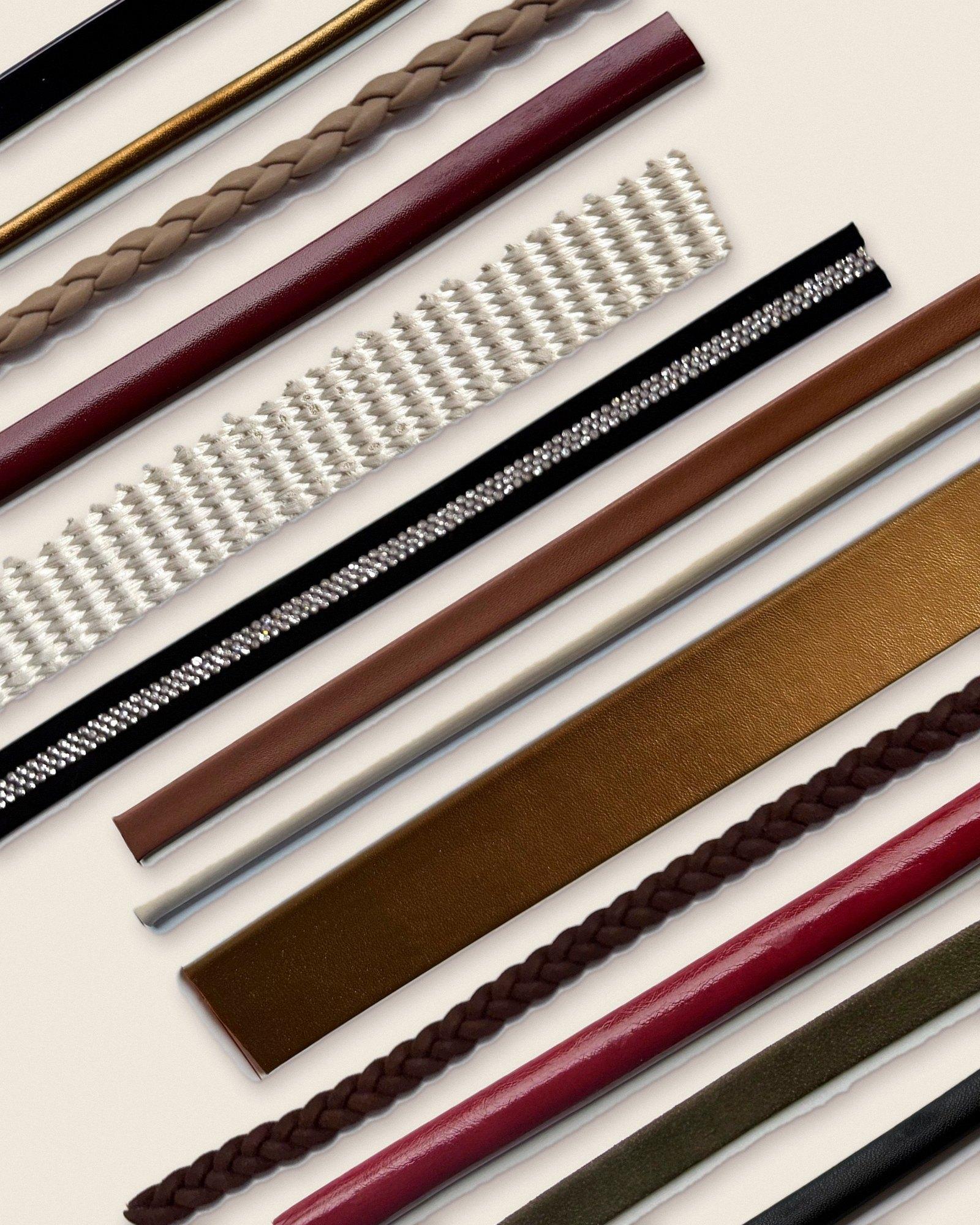 Composição com tiras DoraBella em diagonal: verniz preto, meia cana dourada, trançada nude, vinho, tecido off-white, strass, caramelo, bronze e oliva